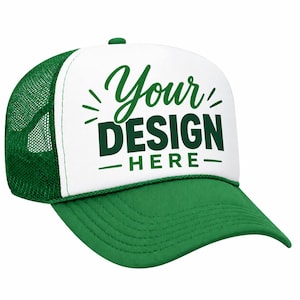 May include: A green and white trucker hat featuring a white foam front panel with the dark green text "Your DESIGN HERE" printed in a mix of script and block fonts. The cap includes a green mesh back, a green brim, and a green plastic snapback.