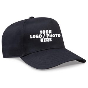 May include: A black baseball cap with a curved brim. The cap features the text "YOUR LOGO / PHOTO HERE" in white block letters across the front. The cap is made of a smooth fabric.