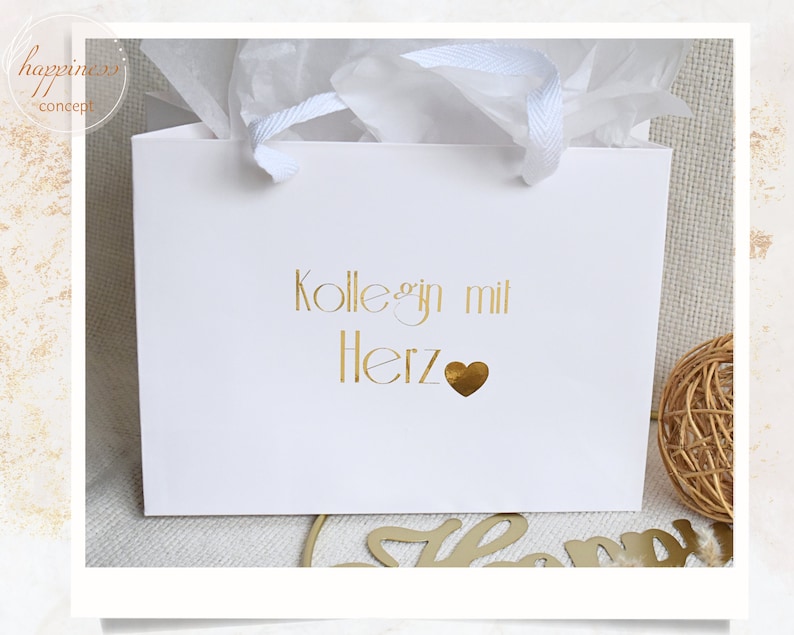 Pu&ograve; includere: Busta regalo bianca con scritta dorata "Kolleg*in mit Herz" e un cuore dorato.