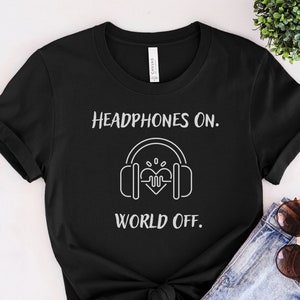 May include: Black t-shirt with white text that reads "Headphones On. World Off." and a graphic of headphones with a heart beat inside.