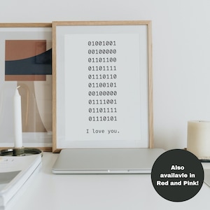 May include: A framed print with a white background and black text. The text is a series of binary code followed by the phrase "I love you.". The print is on a white table with a laptop and candles.