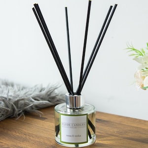 May include: A clear glass diffuser bottle with black reeds and a green label that reads "Clyde Candles Scotland moss & tonka".