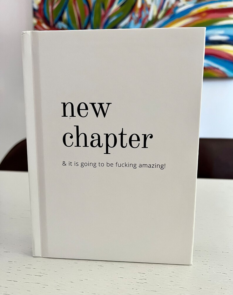 May include: White notebook with the text "new chapter & it is going to be fucking amazing!" printed on the front.