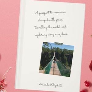 May include: A white hardcover photo album with the text "A passport to memories, stamped with grace, travelling the world, and exploring every new place." A photo is taped to the cover. The name "Amanda Elizabeth" is at the bottom.