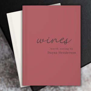 May include: A red hardback journal with the title "wines worth noting by Dayna Henderson" written in black cursive.