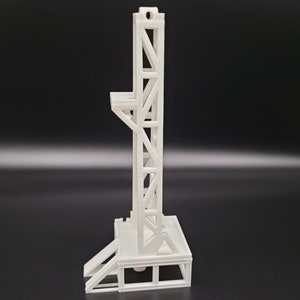 Puede incluir: Modelo de pl&aacute;stico blanco de una estructura alta de marco abierto con una plataforma en la parte superior y una rampa que conduce a ella.