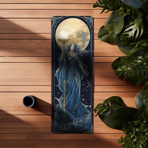Puede incluir: Una esterilla de yoga rectangular con una ilustraci&oacute;n central de una figura con cabello azul fluido y un vestido largo azul, sosteniendo un bast&oacute;n dorado alto rematado con un orbe brillante. El fondo muestra una luna llena y un cielo estrellado.