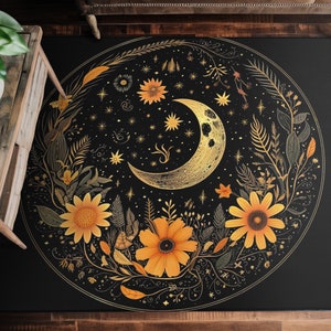 May include: A black and gold round rug with a crescent moon and floral design. The moon is surrounded by stylized flowers and leaves, all in gold. The background is black.