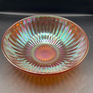 May include: A vintage iridescent glass bowl with a scalloped edge and a starburst pattern in the centre. The bowl is a deep amber colour with a rainbow sheen.