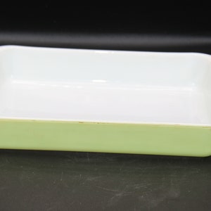 May include: A light green rectangular baking dish with a white interior. The dish is made of glass and has a smooth, glossy finish.