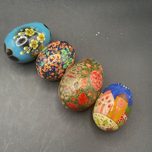 Pode incluir: Quatro ovos decorativos pintados com padrões florais e geométricos coloridos. Os ovos são de madeira e são uma adição única e bela a qualquer decoração de casa.