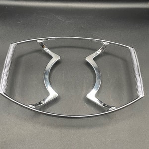 Könnte beinhalten: Ein silberner Metalldrahtrost zum Abkühlen von Backwaren. Der Rost hat eine gebogene Form und zwei Griffe an den Seiten.