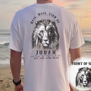 Może przedstawiać: Biała koszulka z czarno-białym nadrukiem lwa z tyłu. Nadruk zawiera tekst "Hail, Lion of Judah, Let the Lion Roar".