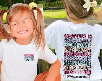 May include: Two white t-shirts with colorful text. One shirt says "Focus on the Good" and the other says "Whatever is Honorable...Think About These Things." The shirts are worn by two young children.