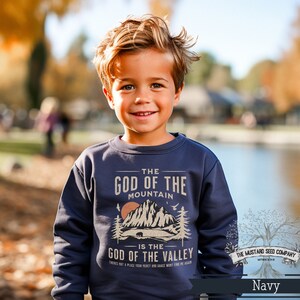 May include: A navy blue sweatshirt with a graphic design featuring a mountain range and the text "The God of the Mountain is the God of the Valley". The text is in a vintage style font and the graphic is in a muted brown color.