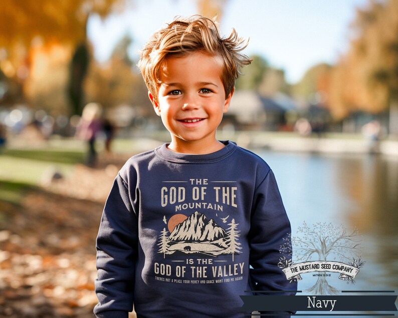 May include: A navy blue sweatshirt with a graphic design featuring a mountain range and the text "The God of the Mountain is the God of the Valley". The text is in a vintage style font and the graphic is in a muted brown color.