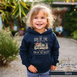 Puede incluir: Una sudadera con capucha azul marino con un estampado gr&aacute;fico de monta&ntilde;as y el texto "The God of the Mountain is the God of the Valley".