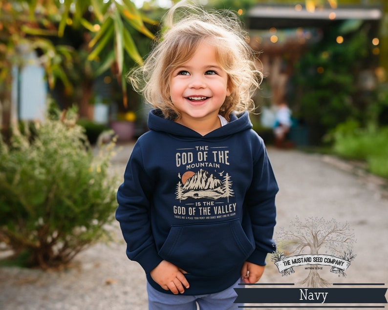 Puede incluir: Una sudadera con capucha azul marino con un estampado gr&aacute;fico de monta&ntilde;as y el texto "The God of the Mountain is the God of the Valley".