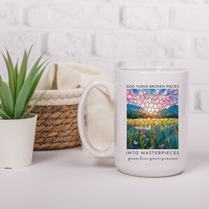 Pu&ograve; includere: Tazza da caff&egrave; in ceramica bianca con un design a mosaico di vetro colorato di un tramonto su un campo. Il testo "God turns broken pieces into masterpieces give him your pieces" &egrave; stampato sulla tazza.