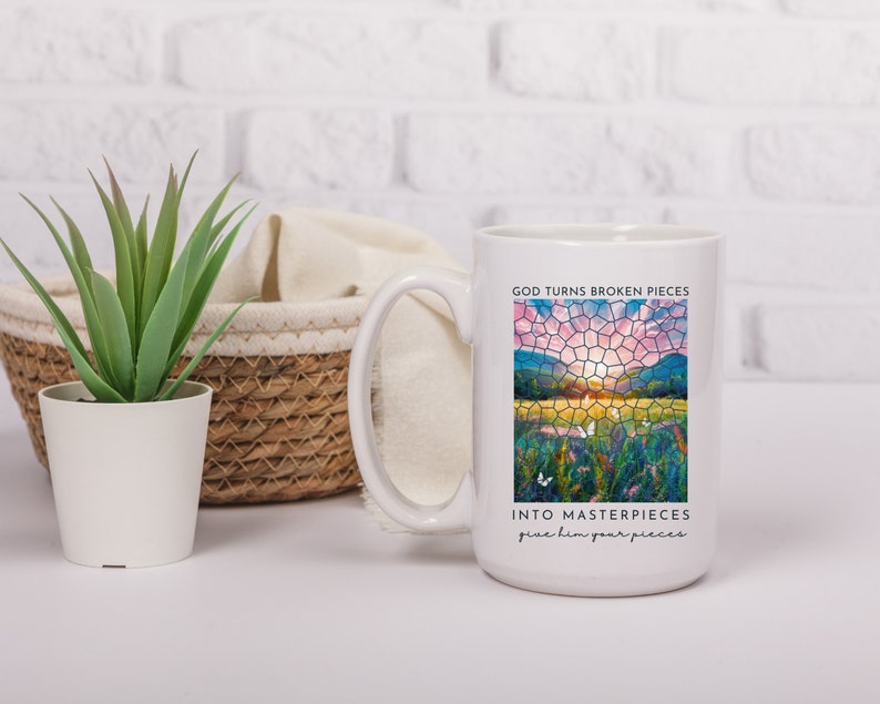 Pu&ograve; includere: Tazza da caff&egrave; in ceramica bianca con un design a mosaico di vetro colorato di un tramonto su un campo. Il testo "God turns broken pieces into masterpieces give him your pieces" &egrave; stampato sulla tazza.