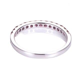 May include: A silver band ring with a row of small pink gemstones set in a pave setting.