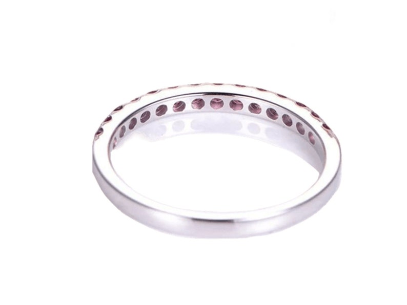 May include: A silver band ring with a row of small pink gemstones set in a pave setting.