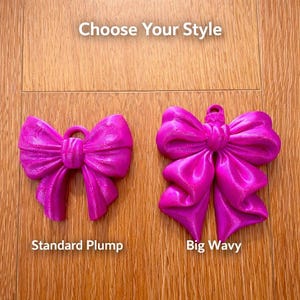 May include: Two fuchsia-colored bow ornaments are displayed on a wooden surface. The text "Choose Your Style" is at the top. One bow is labeled "Standard Plump," and the other is labeled "Big Wavy."