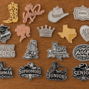 May include: A collection of acrylic charms featuring various designs including cowboy boots, hats, crowns, the state of Texas, hearts, and graduation themes. The charms display text such as Howdy, Class of 2026, 2027, Freshman, Sophomore, Junior, and Senior.