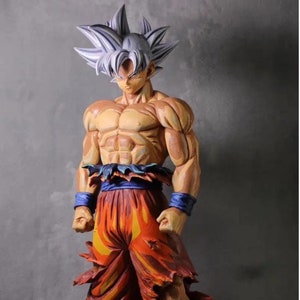 Op de afbeelding: Een gedetailleerd beeldje van een personage met wit haar en een gespierd lichaam. Het personage draagt een oranje broek met blauwe accenten en een blauwe riem. Het beeldje staat in een vechtpose.