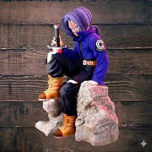 Puede incluir: Figura de un personaje con cabello morado, vistiendo una chaqueta azul con un parche de "Capsule Corp", pantalones negros y botas color canela. El personaje está sentado en una piedra y sosteniendo una espada. El fondo es una pared de madera.