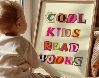 May include: A framed print with the text "COOL KIDS READ BOOKS" in colorful, cut-out letters on a light yellow background. A toddler is looking at the print, sitting on a striped blanket with a brown teddy bear.