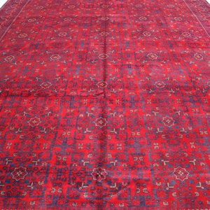May include: A red rug with a blue and white geometric pattern. The rug has a fringe border.