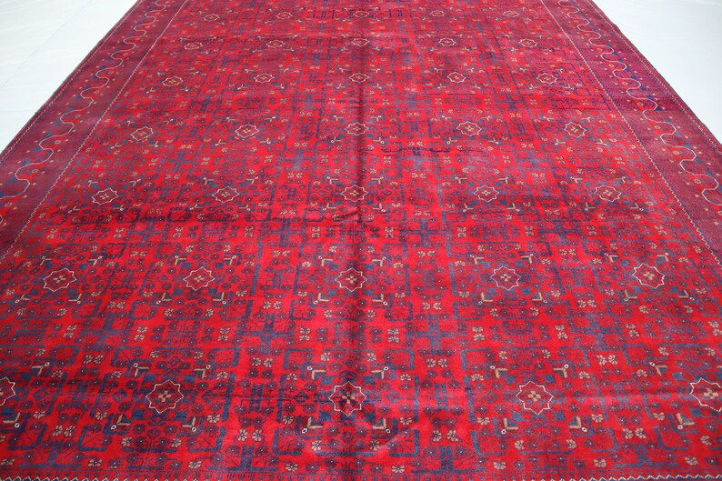 May include: A red rug with a blue and white geometric pattern. The rug has a fringe border.