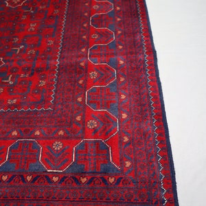 May include: A red and blue rug with a traditional Persian design. The rug has a fringe border and intricate patterns throughout.