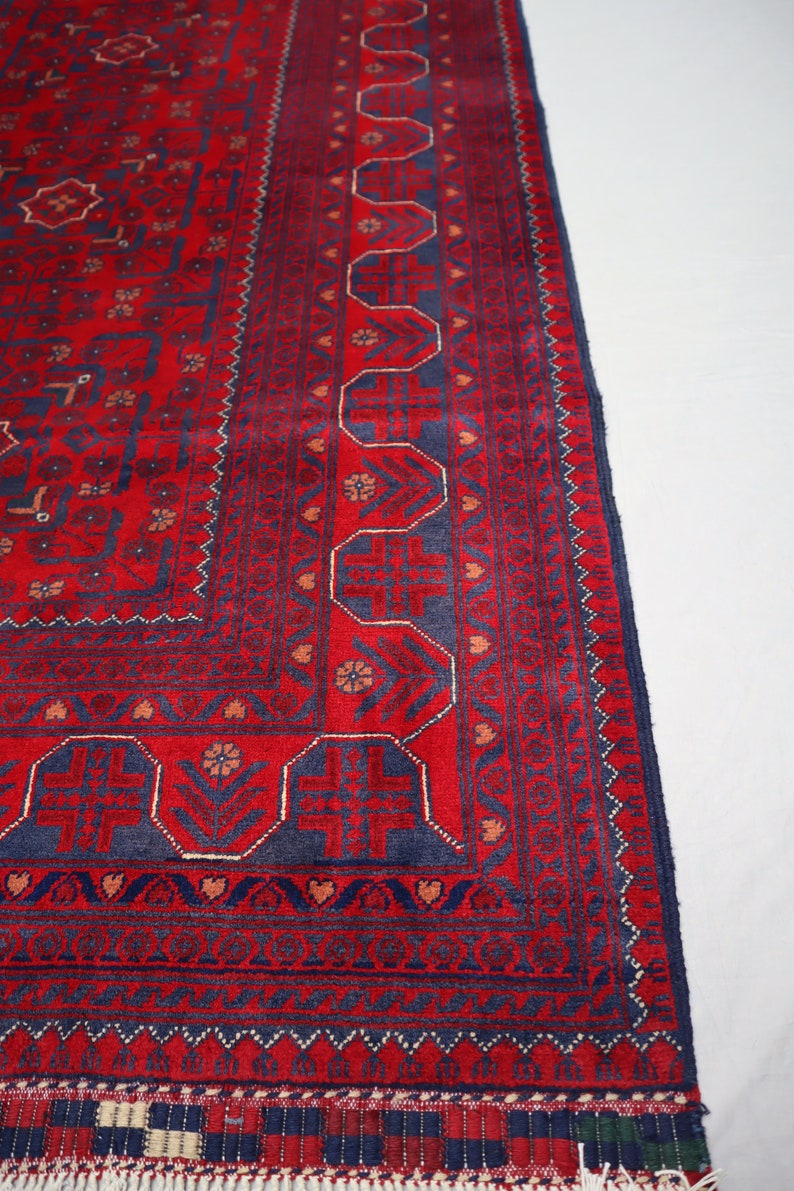 May include: A red and blue rug with a traditional Persian design. The rug has a fringe border and intricate patterns throughout.