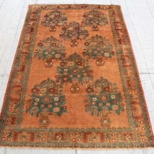May include: A rectangular area rug featuring a vibrant orange background with a repeating pattern of seven floral arrangements in vases. The motifs are rendered in shades of teal, dark green, and red, framed by a decorative border with floral details.