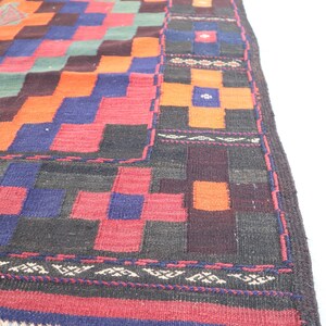 May include: A colorful, geometric patterned rug with a fringe border. The rug features a mix of red, orange, blue, green, and black colors.