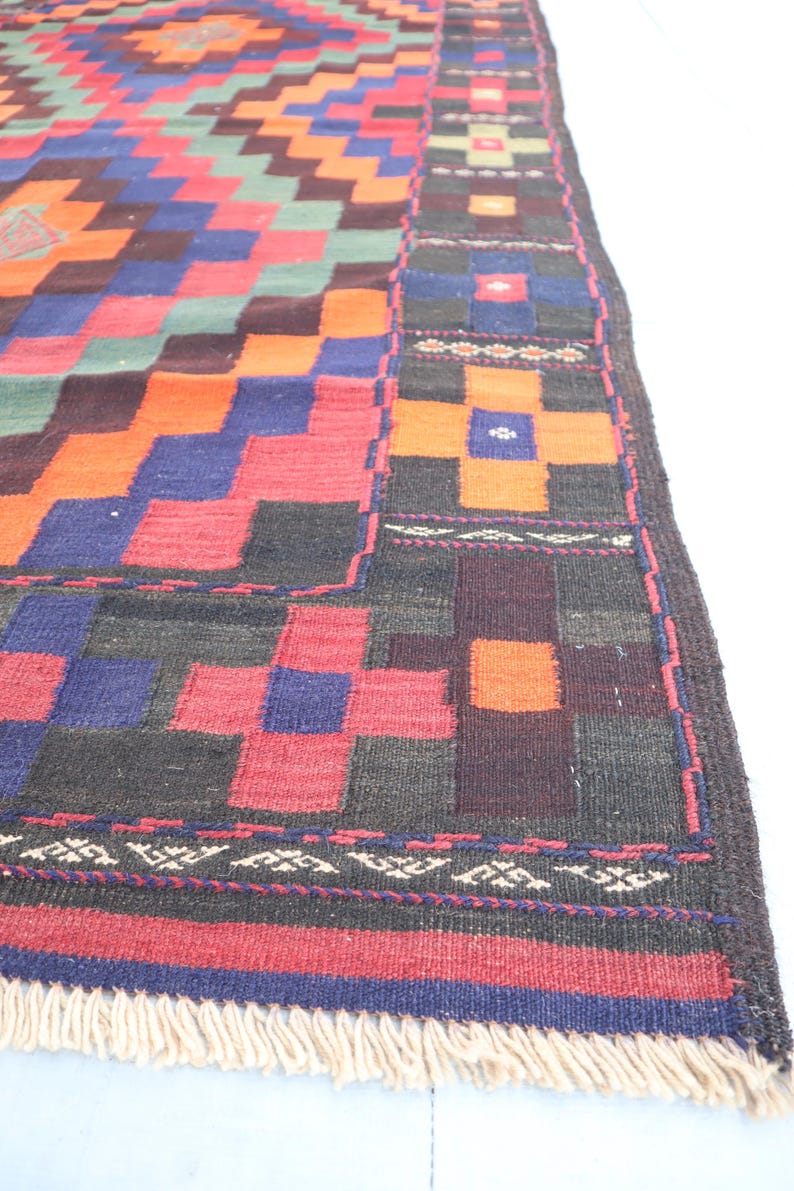 May include: A colorful, geometric patterned rug with a fringe border. The rug features a mix of red, orange, blue, green, and black colors.