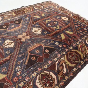 May include: A vintage rug with a geometric pattern in shades of brown, red, blue, and beige. The rug has a central medallion and a border with floral motifs.