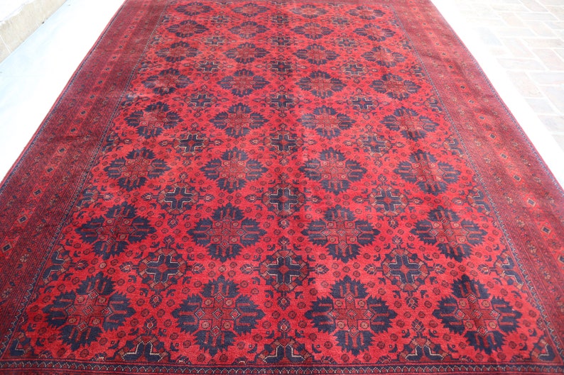 May include: A red and blue rug with a traditional Persian design. The rug has a geometric pattern with intricate details.