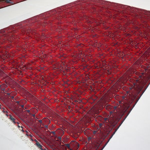 May include: A red rug with a blue and gold floral pattern. The rug has a fringe border.
