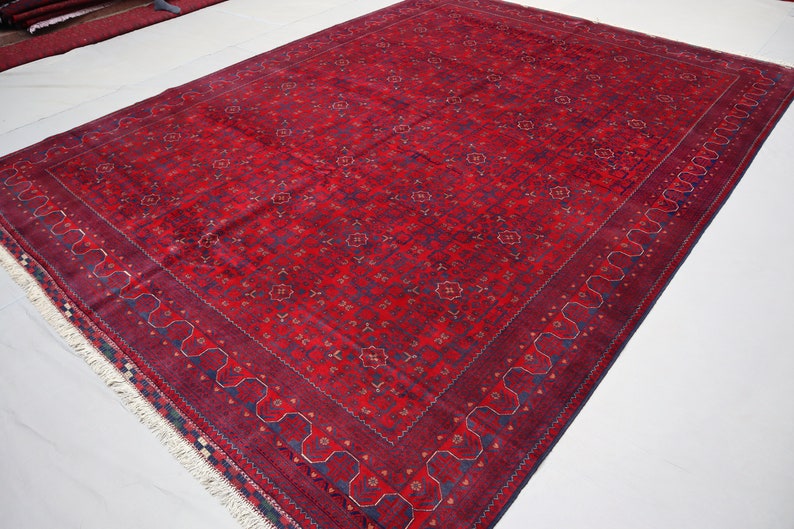 May include: A red rug with a blue and gold floral pattern. The rug has a fringe border.