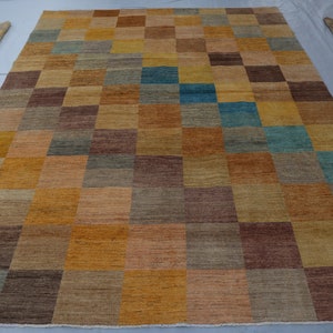 Puede incluir: Una alfombra rectangular grande con un patrón de cuadros en tonos marrones, beige y azules. La alfombra está hecha de un material suave y tejido.