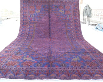 May include: A large, intricately patterned rug with a deep blue background and a central diamond shape. The rug features a repeating design of stars, flowers, and geometric shapes in shades of pink, red, and brown.