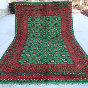 K&ouml;nnte beinhalten: Ein gr&uuml;ner und roter Teppich mit geometrischem Muster. Der Teppich hat einen Fransenrand.