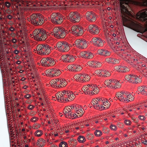 Puede incluir: Una alfombra roja con un diseño persa tradicional. La alfombra tiene un medallón central con intrincados patrones geométricos y un borde con motivos repetidos.