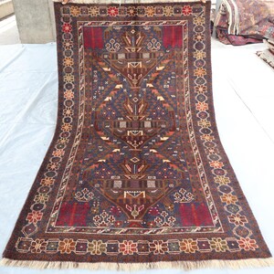 May include: A traditional Persian rug with a dark blue background and intricate floral and geometric patterns in shades of red, brown, and beige. The rug has a fringe border.