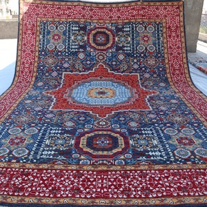 May include: A large, intricately patterned rug with a red, blue, and gold color scheme. The rug features a central medallion with a geometric design and a border with floral motifs.