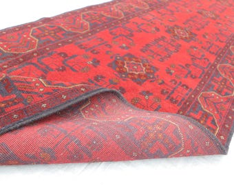 Könnte beinhalten: Ein roter und blauer Teppich mit Muster und Fransen. Der Teppich ist in der Mitte gefaltet, so dass die Rückseite sichtbar ist.