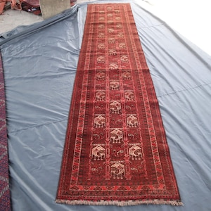 Puede incluir: Dos alfombras de color rojo y crema con patrones dispuestas sobre una superficie gris. Las alfombras tienen diseños intrincados y ambas tienen aproximadamente 90 cm de ancho.